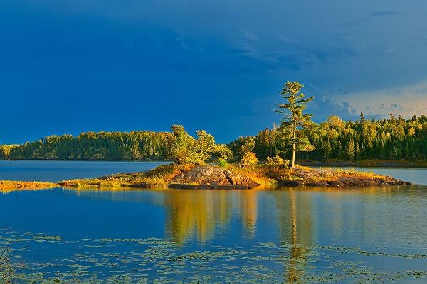 Canada-Ontario-Kenora District Forest autumn colors reflect on Middle Lake at sunset